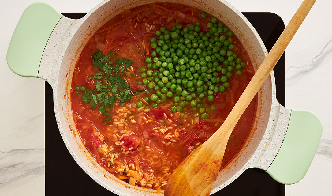 Ervilhas e coentros no tacho com os outros ingredientes